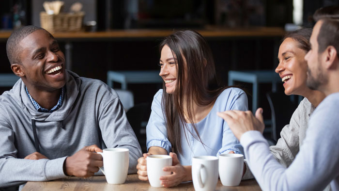 group of younger adults sitting in a coffee shop talking and laughing