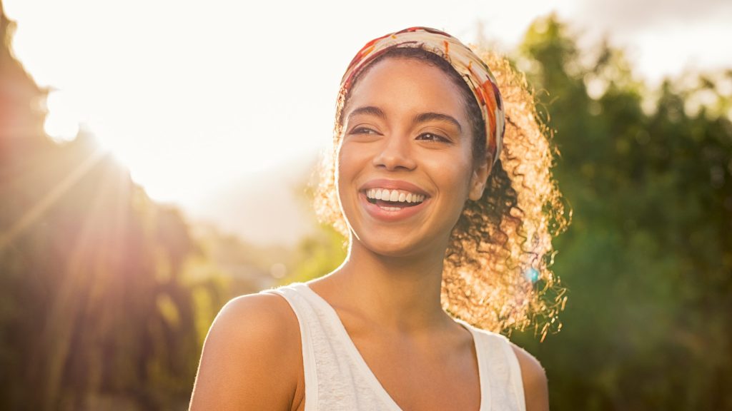 Young woman smiling with the sun behind her