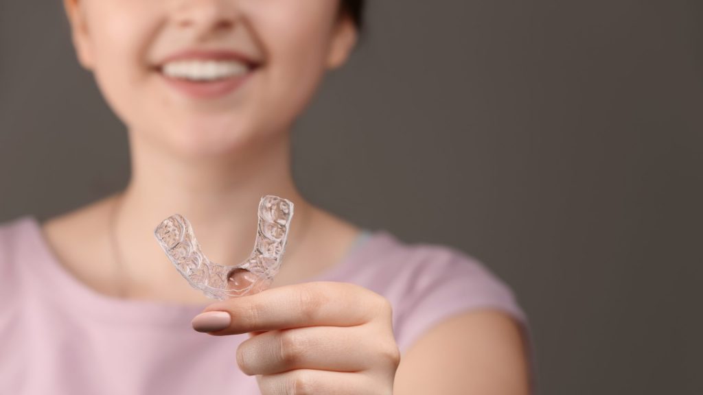 Woman With Occlusal Splint On Grey Background, Closeup