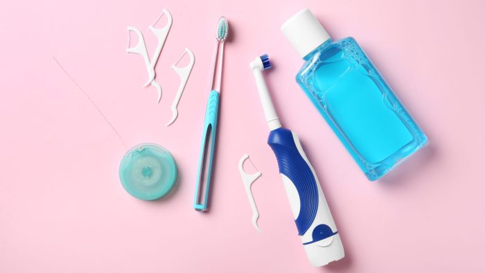 A collection of oral hygiene items on a pink background Portage MI dentist