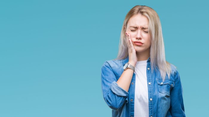 Young woman holding face in pain cavity Portage MI dentist